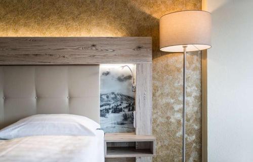 a bedroom with a bed and a lamp and a mirror at Panorama Hotel Turracher Höhe in Turracher Hohe