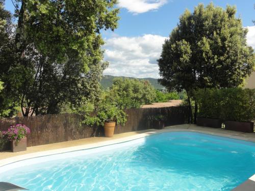 a large blue swimming pool with a fence and trees at Gîtes Les 3 Cigales in Vallon-Pont-dʼArc