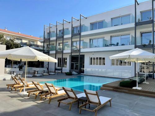 Una piscina con sillas y sombrillas frente a un edificio. en Mythical Sands Resort, Protaras, Choose Joy Apt, en Paralimni