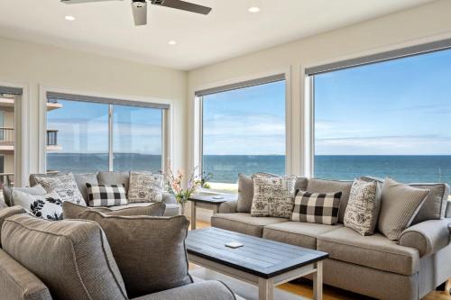 a living room with a couch and a table and windows at Oceanfront Home Beach Access Deck & Ping Pong in Old Orchard Beach