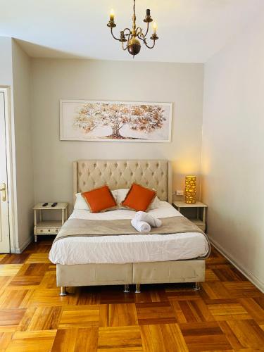 a bedroom with a bed with orange pillows and a chandelier at BbCasita Blue in Santiago