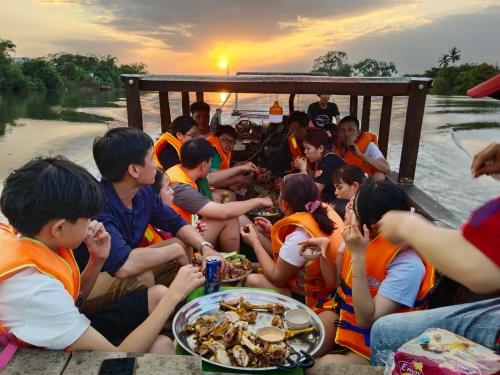 a group of people sitting on a boat eating food at Điểm Hẹn restaurant, cắm trai, sở thú mini farm, câu cá giải trí 