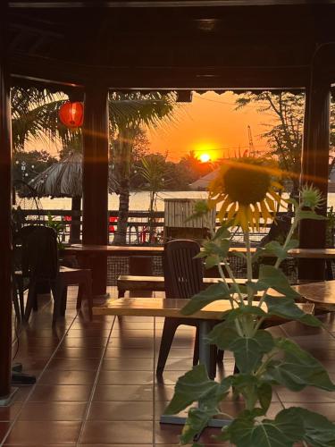 a sunflower sitting at a table with a sunset in the background at Điểm Hẹn restaurant, cắm trai, sở thú mini farm, câu cá giải trí 