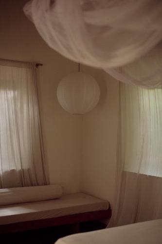 a bedroom with a bed and a window with curtains at The Kip in Ahangama