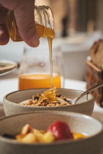 a person pouring honey into a bowl of food at Elysia Boutique Hotel in Chania Town