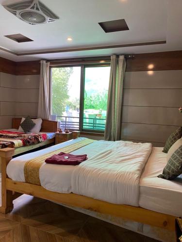 two beds in a room with a window at Arcadian Resort Skardu in Skardu