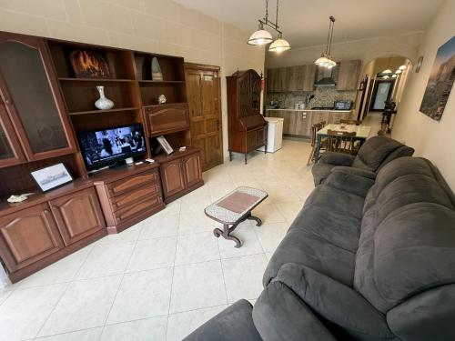 a living room with a large couch and a kitchen at Traditional Maltese 3BD Apartment with Front & Back Balconies - Close to Gozo Ferry in Nadur