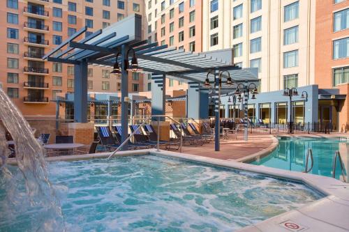einen Pool mit einem Brunnen, Stühlen und Gebäuden in der Unterkunft Wyndham National Harbor 1BR Apartment with Resort Access in Oxon Hill