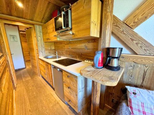 une cuisine dans une cabane en rondins avec une cuisinière et un micro-ondes dans l'établissement Studio Style Chalet pour 3 Pers, Balcon, Pied des Pistes, Réberty 2000 - FR-1-452-85, aux Menuires