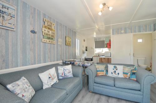 a living room with two blue couches and a kitchen at 13 Hillside in Bude