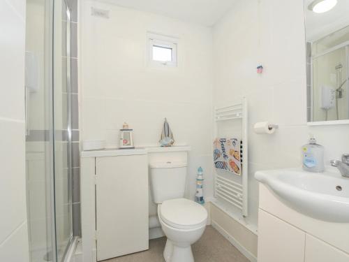 a white bathroom with a toilet and a sink at 13 Hillside in Bude