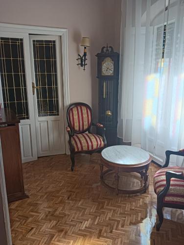 a living room with a table and a chair and a clock at Casa Turística Plaza del Conde in Ciudad-Rodrigo