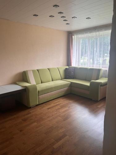 a living room with a green couch in front of a window at Loksahome apartmens in Loksa