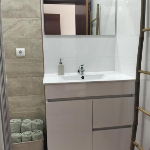 a bathroom with a sink and a mirror and towels at Quartos, Solar da São in Nazaré