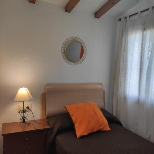 a bedroom with a bed with an orange pillow and a mirror at Villa López in Cómpeta