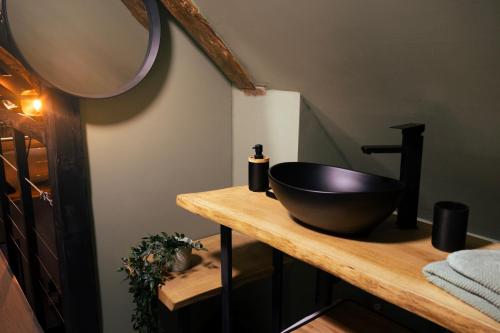 La salle de bains est pourvue d'un lavabo noir sur un comptoir en bois. dans l'établissement TheRubyLodge, à Ourville-en-Caux