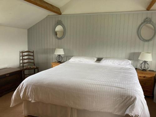 a bedroom with a white bed with two lamps and two mirrors at The Granary in Kirkby Lonsdale