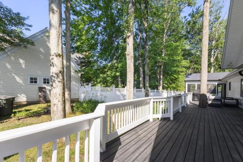 a wooden deck with a white fence and trees at Living My Best Life in Union Pier
