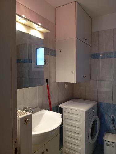 a bathroom with a sink and a washing machine at Leonidas Apartments in Preveza