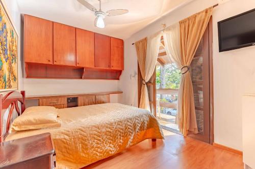 ein Schlafzimmer mit einem Bett, einem Fernseher und einem Fenster in der Unterkunft Espaçosa Casa a 200 Metros da Praia de Bombas in Bombas