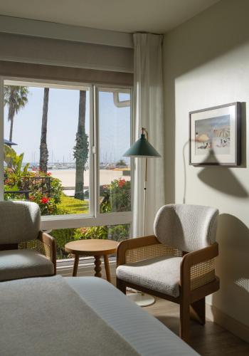 a bedroom with a bed and two chairs and a window at The Milo in Santa Barbara