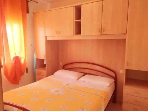 ein kleines Schlafzimmer mit einem Bett und Holzschränken in der Unterkunft Apartments in Rosolina Mare 48309 in Rosolina Mare