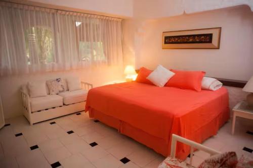 a bedroom with a large red bed and a couch at Hermosa Villa en Ixtapa Zihuatanejo ideal para Parejas y Familia in Ixtapa