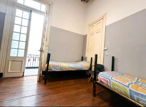 a room with two beds and a window and a door at IDEAL SOCIAL Hostel in Buenos Aires