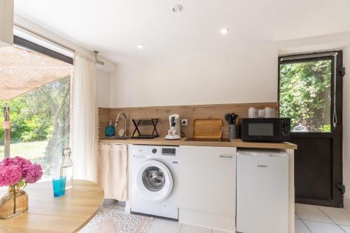 a washing machine in a kitchen with a window at Les Mappias en Ardèche in Vesseaux