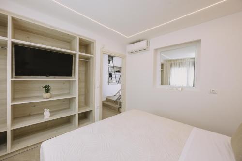 a white bedroom with a bed and a flat screen tv at Pasiphae Luxury villa in Agia Pelagia