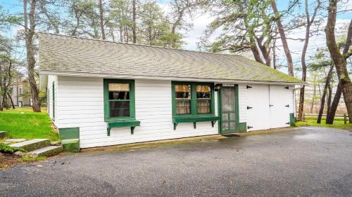 a small white house with green windows in a yard at Beachside Oceanside Walk onto the beach in Saco