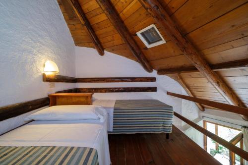 two beds in a room with wooden ceilings at Cugnana Porto Rotondo Bungalows - Camping in Cugnana