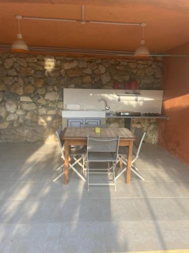 a table and chairs in a room with a stone wall at Bas de villa 2 à 5 couchages in Évenos