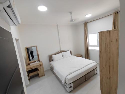 a small bedroom with a bed and a mirror at Al Anwar Building Luxury in Salalah
