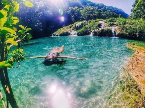 a person laying in the water in front of a waterfall at La Estancia in Lanquín