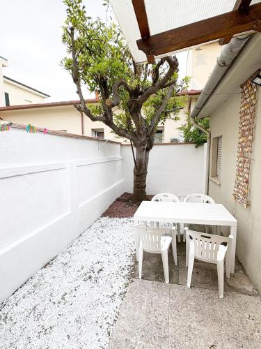 a white table and two chairs and a tree at Oasi del Pescatore in Marina di Cecina