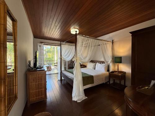 a bedroom with a canopy bed and a window at Pousada Corsario Buzios in Búzios