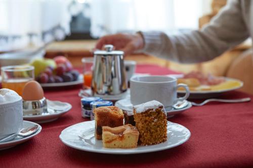a table topped with plates of pastries and cups of coffee at Hotel Garni dello Sportivo in Madonna di Campiglio