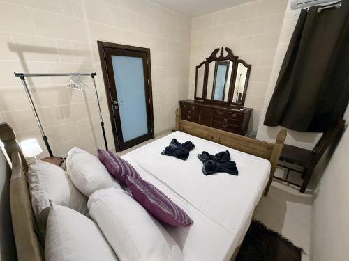 a bedroom with a white bed with purple pillows and a couch at Traditional Maltese 3BD Apartment with Front & Back Balconies - Close to Gozo Ferry in Nadur
