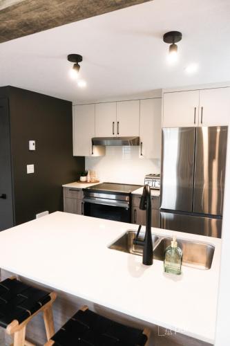 a kitchen with a white counter top and a refrigerator at Studio 21 charme et confort au coeur de Magog in Magog-Orford
