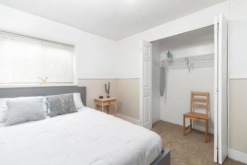 a bedroom with a white bed and a chair at Cozy Millcreek Home SLC in Millcreek
