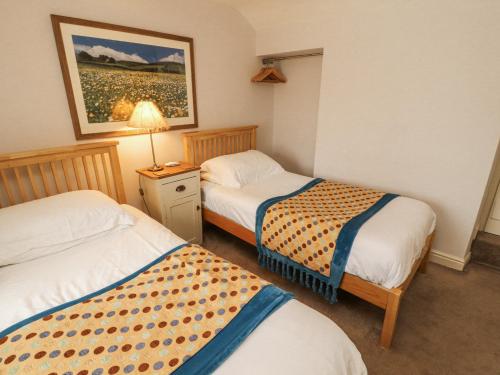 a hotel room with two beds and a lamp at Corner Cottage in Carnforth