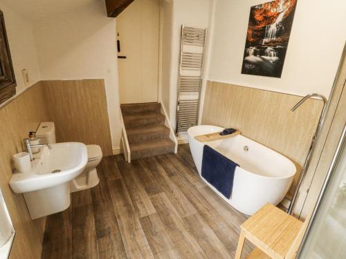 a bathroom with a tub and a toilet and a sink at Corner Cottage in Carnforth