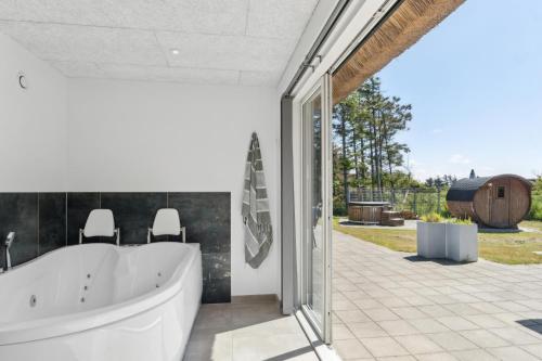 une salle de bain avec une grande baignoire blanche et un patio dans l'établissement Feriehus 3003, à Ringkøbing