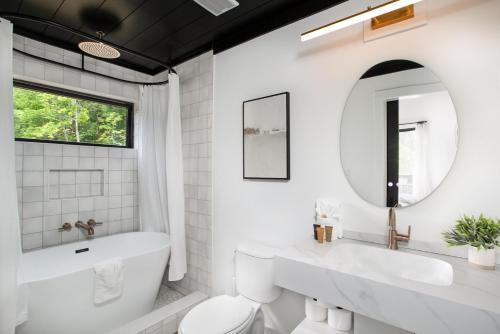 a bathroom with a tub and a toilet and a sink at The Little Timber Cozy Hot Tub Fireplace in Townsend