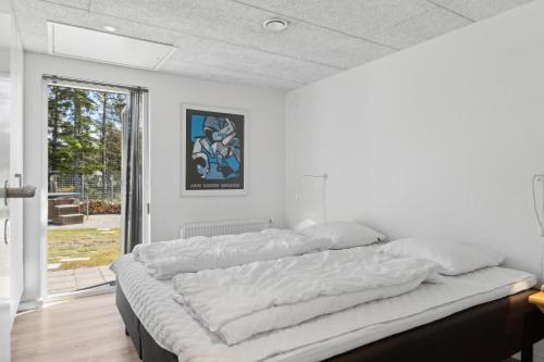 Cette chambre blanche dispose d'un grand lit et d'une fenêtre. dans l'établissement Feriehus 3003, à Ringkøbing