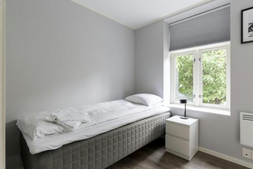 a bed in a white room with a window at Central and Spacious Apartment for 6 in Trondheim
