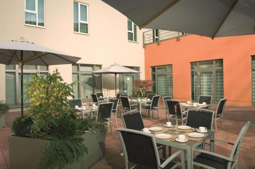 an outdoor patio with tables and chairs and umbrellas at NH Collection Nürnberg City in Nürnberg
