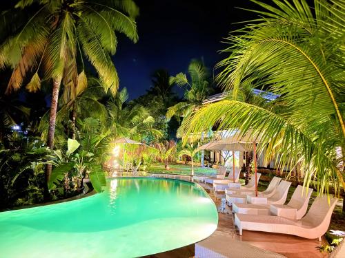 a pool at night with lounge chairs and palm trees at Kelingking Tropical in batumadeg