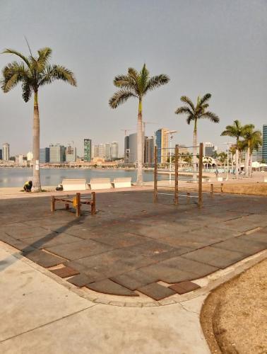 a park with benches and palm trees near the water at Apart T 0 Studio or Flat Style in Downtown in Luanda